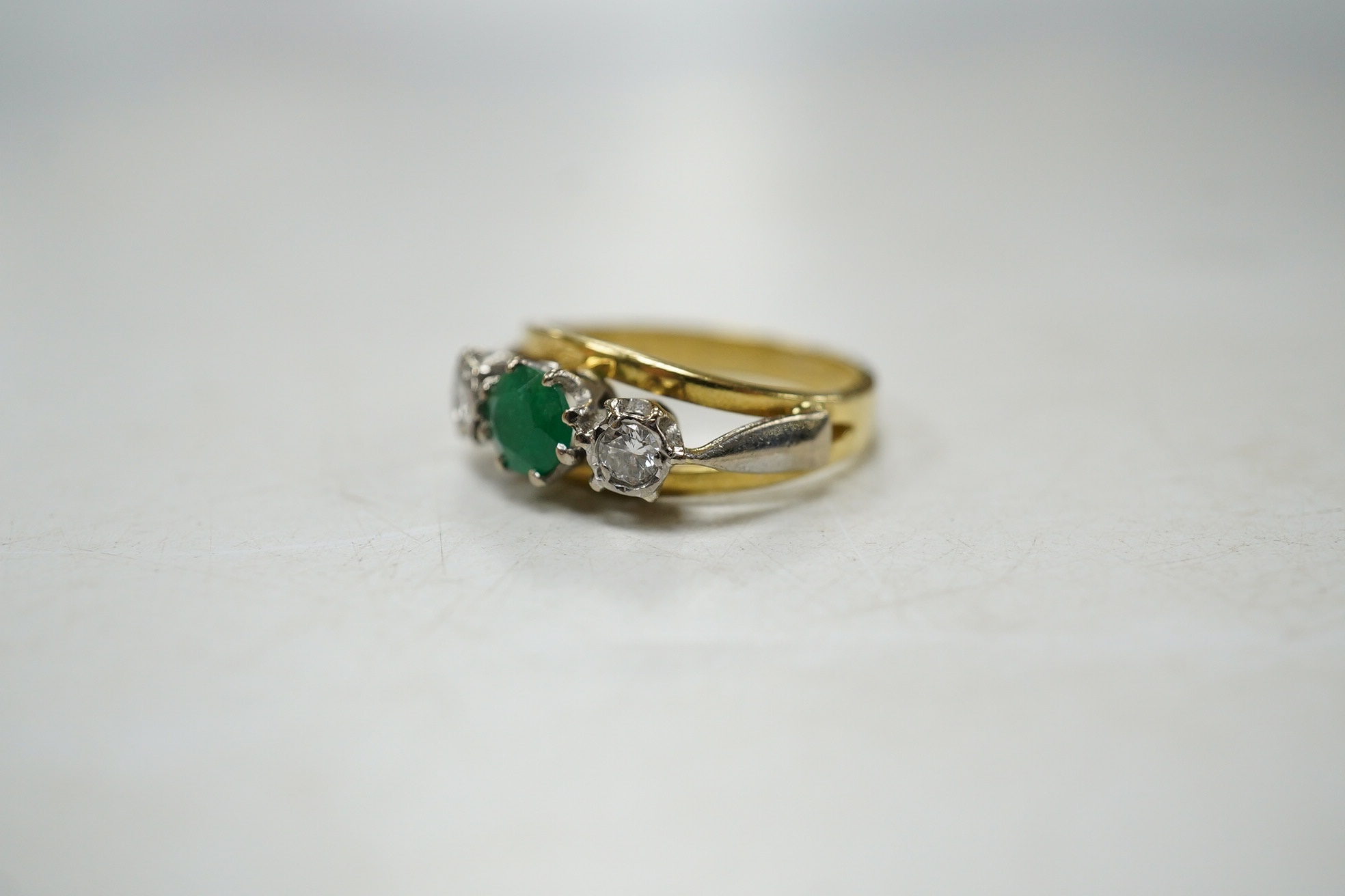 A modern yellow metal, emerald and diamond set three stone ring, size G, gross weight 3.8 grams. Condition - fair